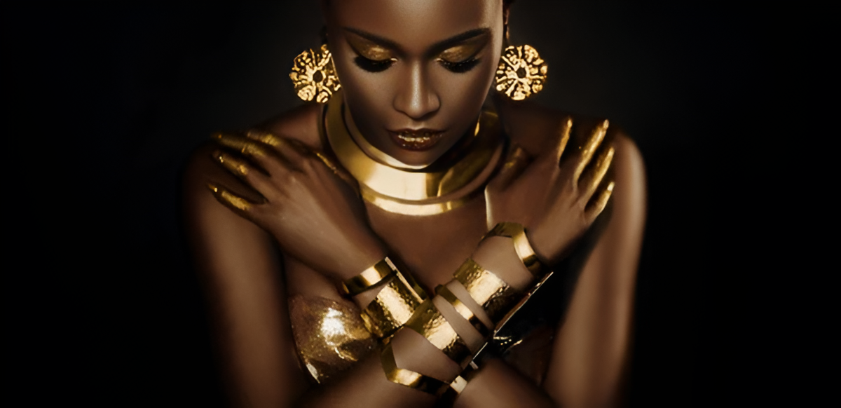 Woman with gold jewelry and makeup against a black background